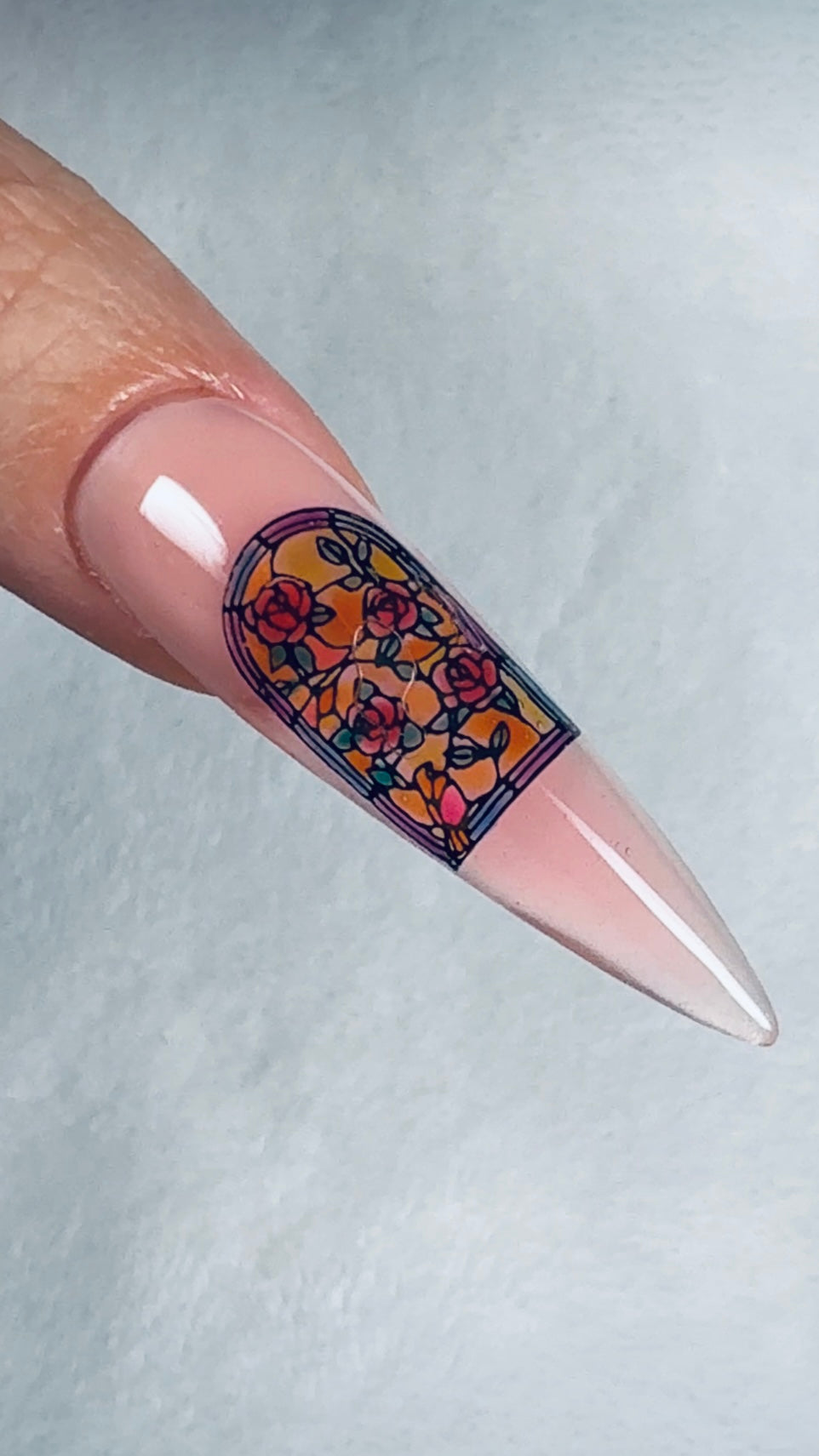 Nail with decorative sticker featuring floral design on a light gray background