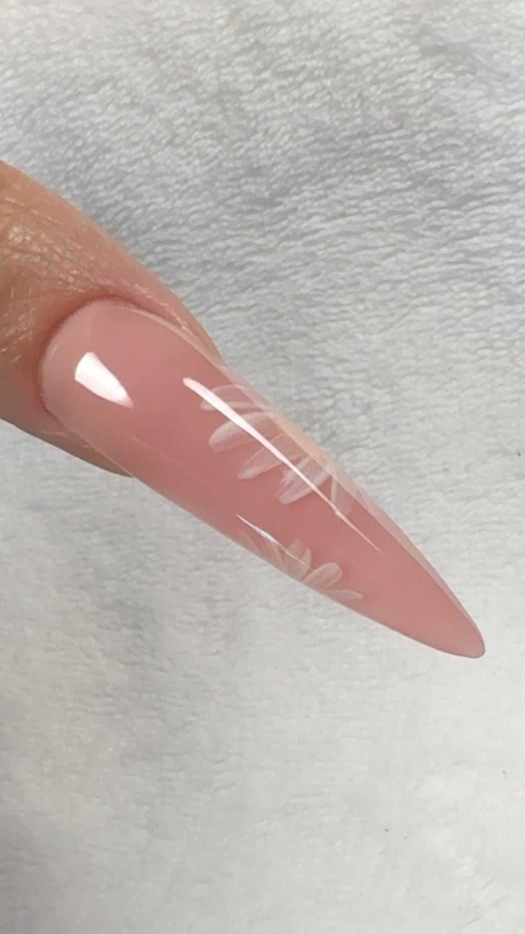 Long, pink nail on a light gray background