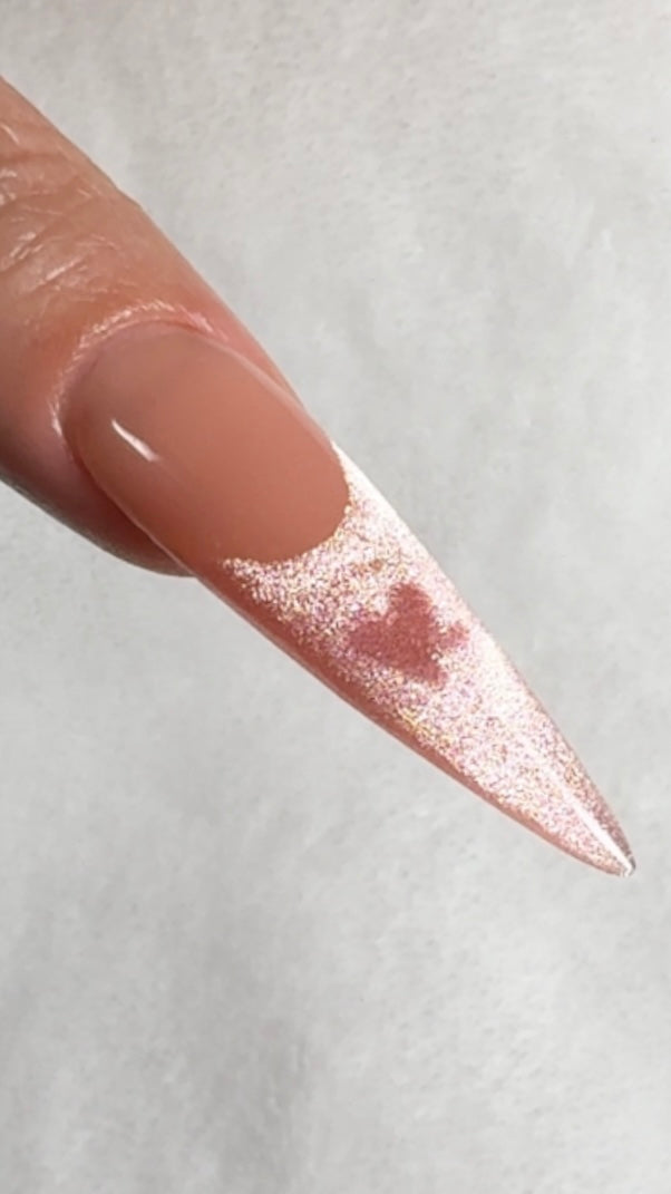 Nail with a metallic pink polish on a light gray background